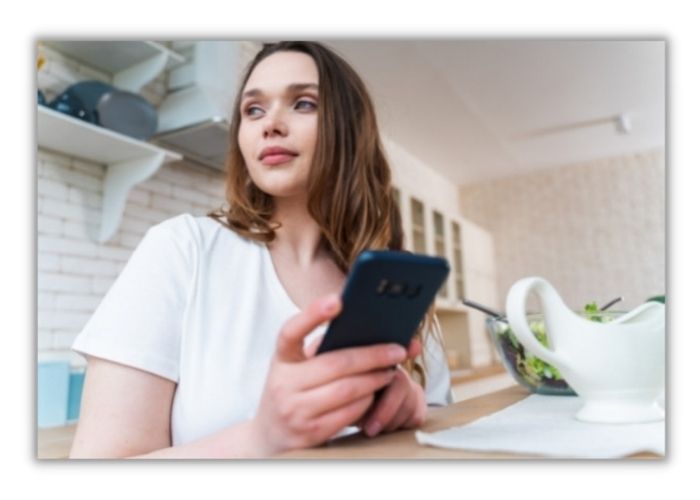 woman sat with cellphone at desk enjoying online therapy